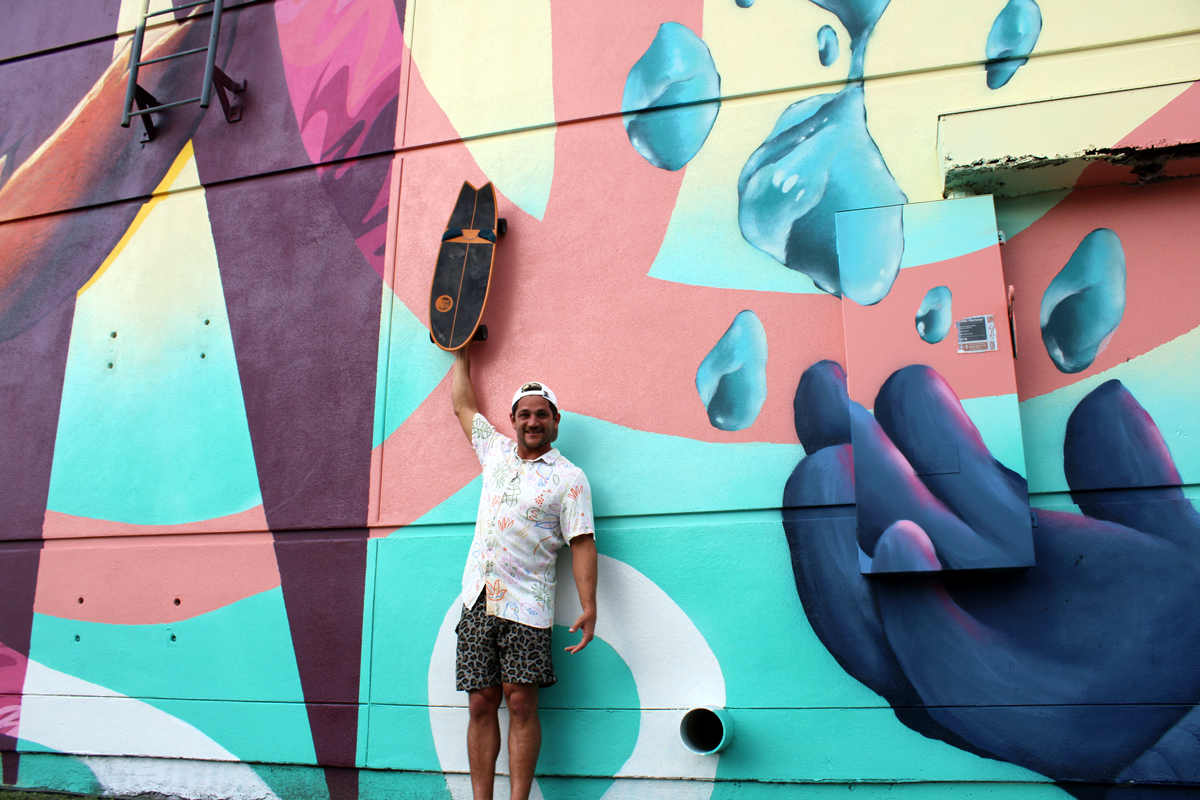 Artist Gabriel Anthony Prusmack with his Skateboard in front of one of his murals