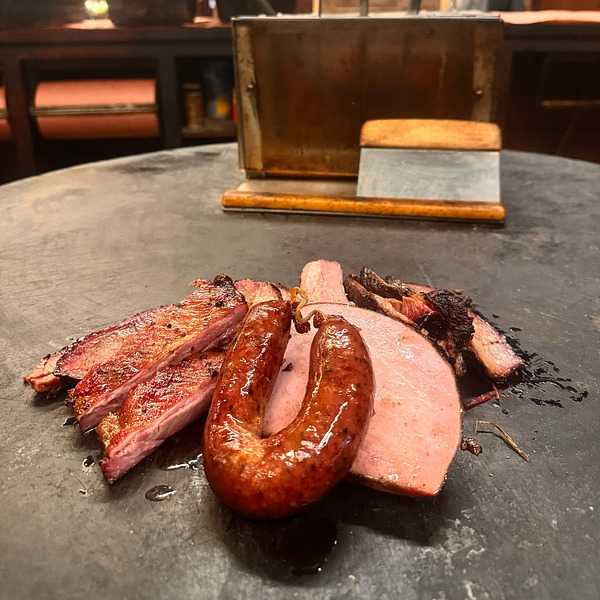 A feast of Texas barbecue perfection—brisket, sausage, and ribs served with a side of history and smoky flavor!