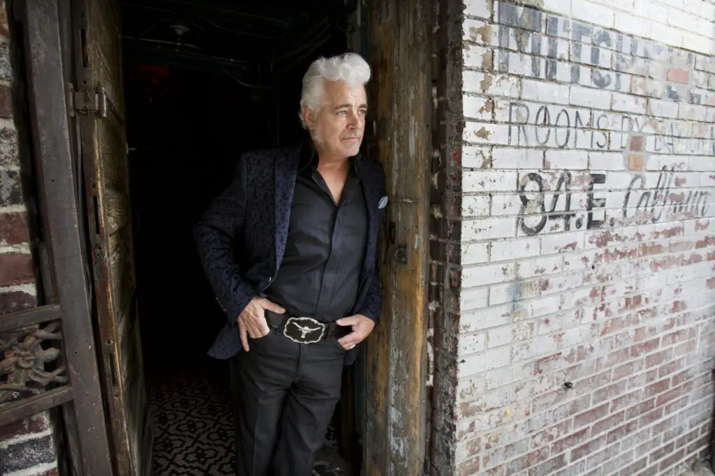 Standing in the doorway of timeless style, a true icon with a gaze that tells the story of country music’s history. | Source: redhouserecords.com