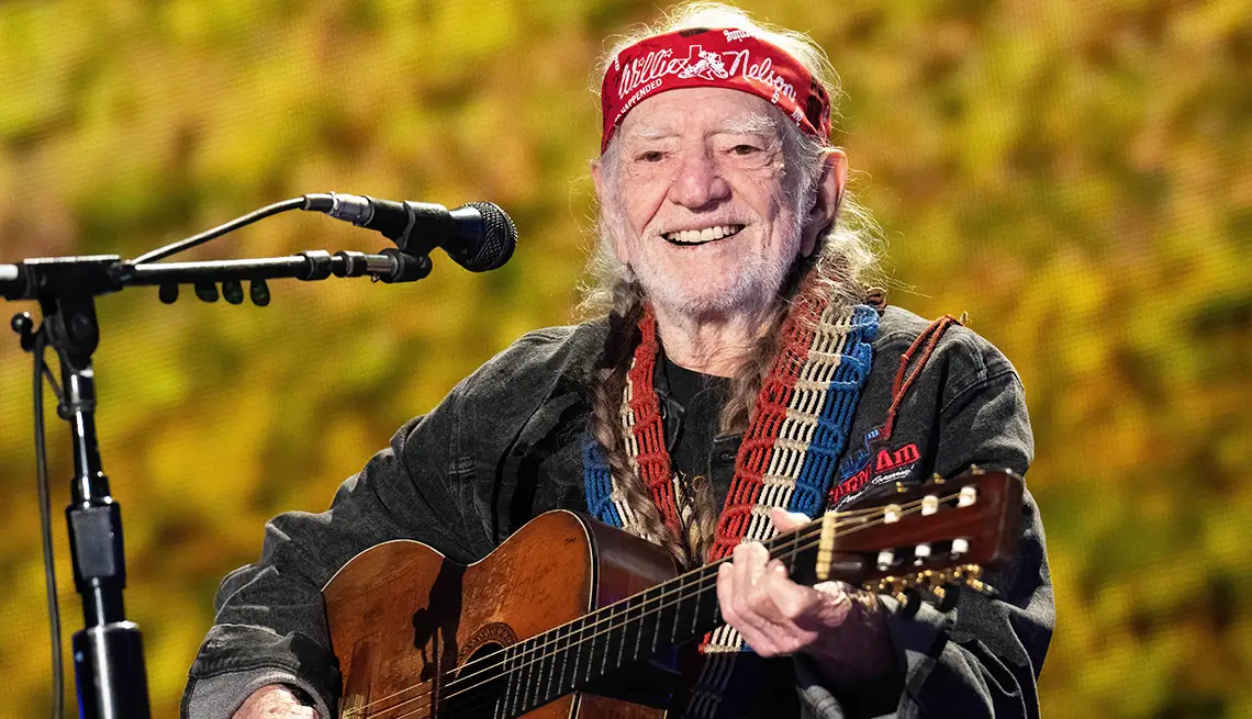 Willie Nelson bringing the soulful sound of country music to life with his iconic guitar and unforgettable smile. | Source: aarp.org