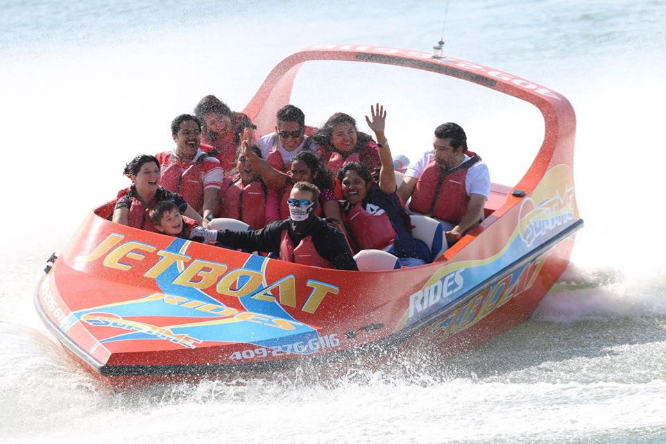 Families wearing life vests enjoy a high-speed, splash-filled jetboat ride on the Gulf waters near Galveston.