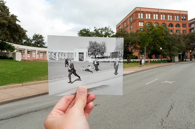 A person holds a historical photo from the JFK assassination over the matching modern-day Dealey Plaza scene in Dallas.