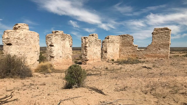 Ruins of historic adobe walls under a blue sky along El Camino Real de Tierra Adentro in the El Paso desert.