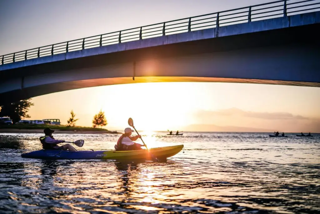 Two people kayaking under a bridge at sunset on South Padre Island.