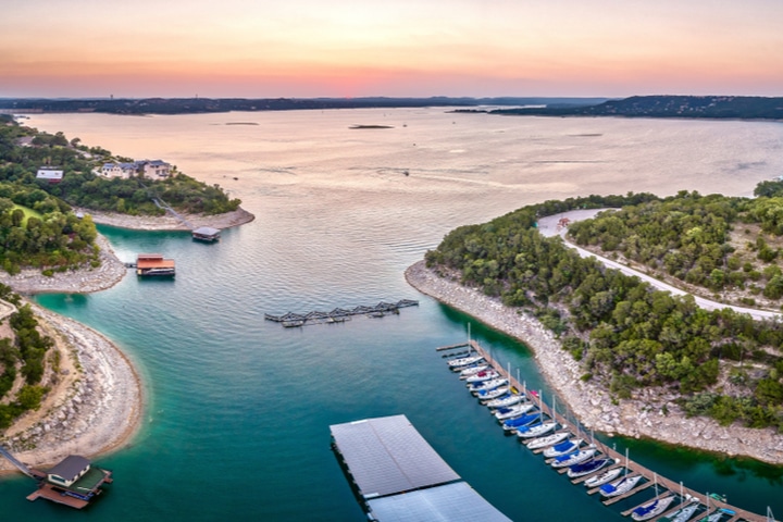 Aerial view of Lake Travis at sunset with marinas and boats docked along the shoreline near Austin, Texas. 