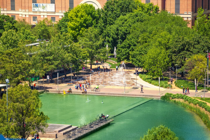 Aerial view of Discovery Green park with fountains, lake, and families walking in downtown Houston.