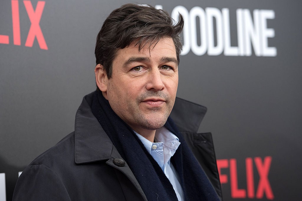 Kyle Chandler is attending a Netflix event, dressed in a coat and scarf.
