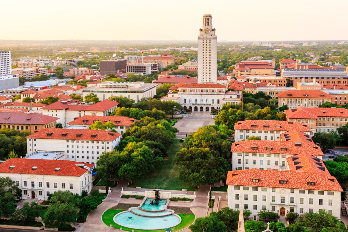 Aerial view of the University of Texas at Austin campus with the Main Tower and surrounding red-roofed buildings, home to the Moody College of Communication.
