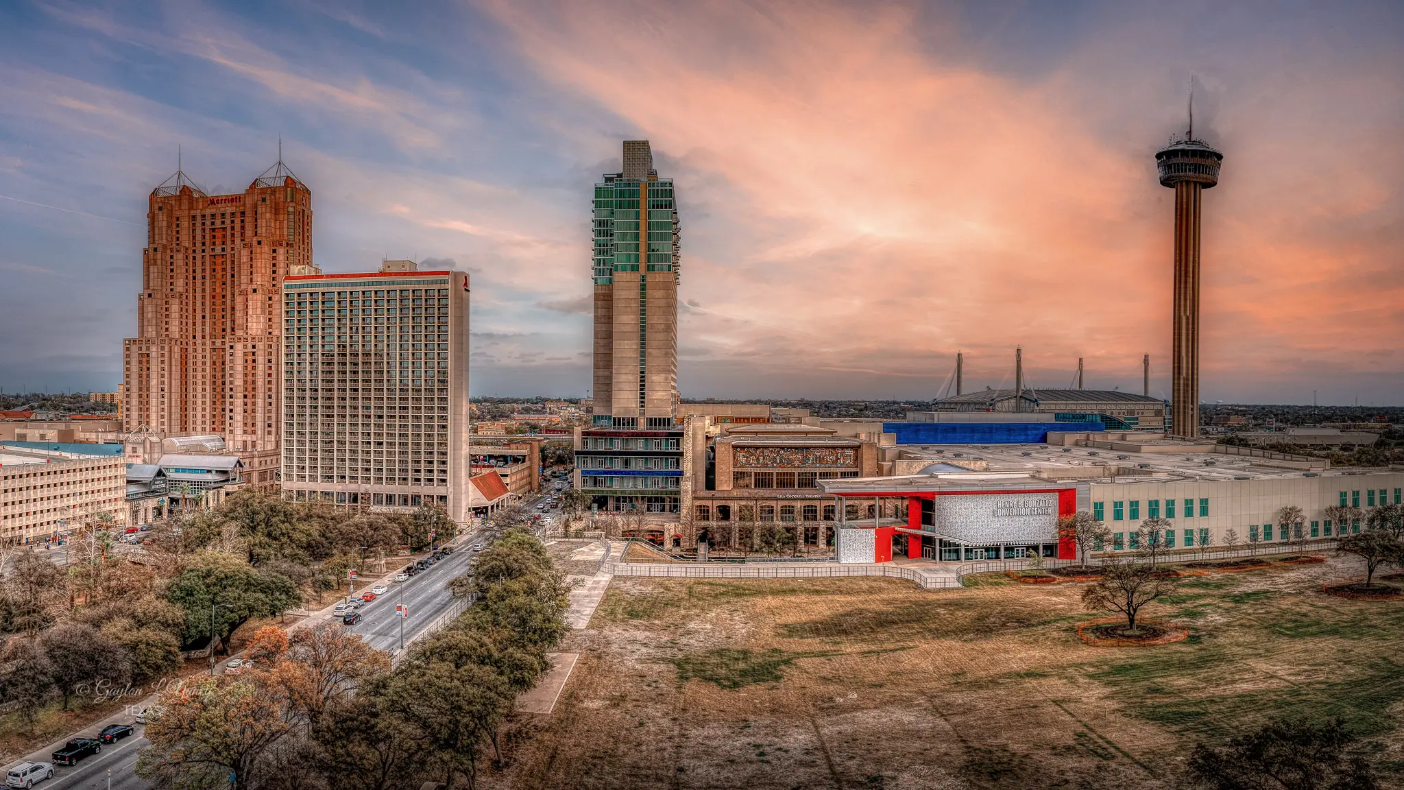 Panoramic view of downtown San Antonio with Tower of the Americas and city buildings at sunset.