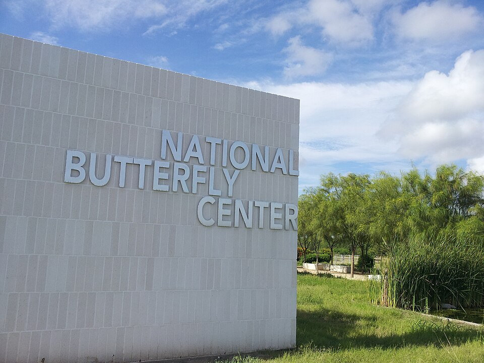 Entrance sign of the National Butterfly Center surrounded by native subtropical plants in Texas.