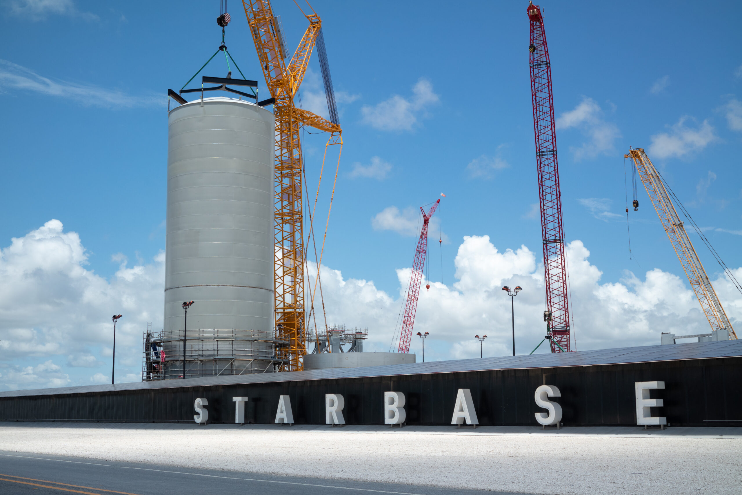 Large rocket tank section with cranes at SpaceX Starbase, highlighting what visitors can see during a trip to Starbase.