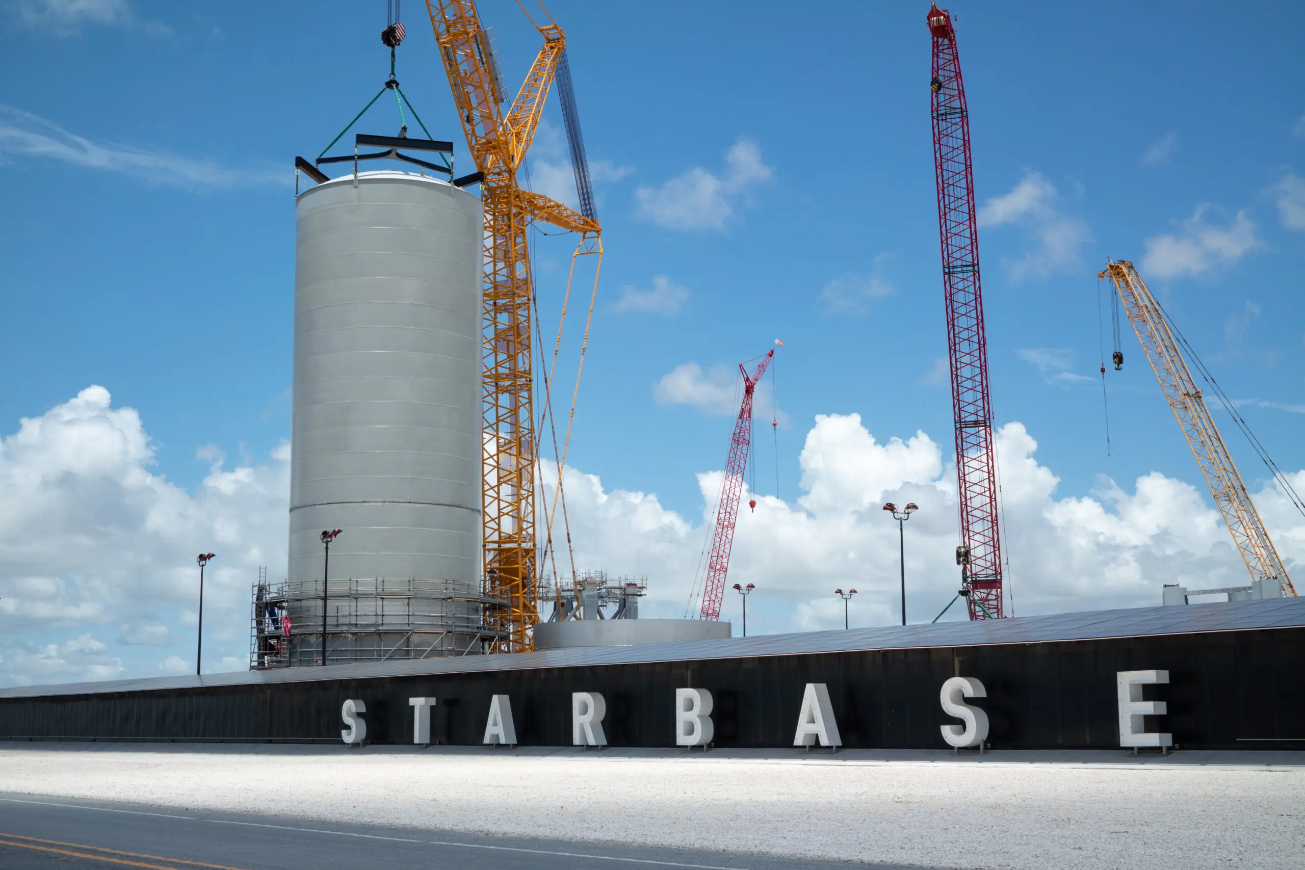 Large rocket tank section with cranes at SpaceX Starbase, highlighting what visitors can see during a trip to Starbase.