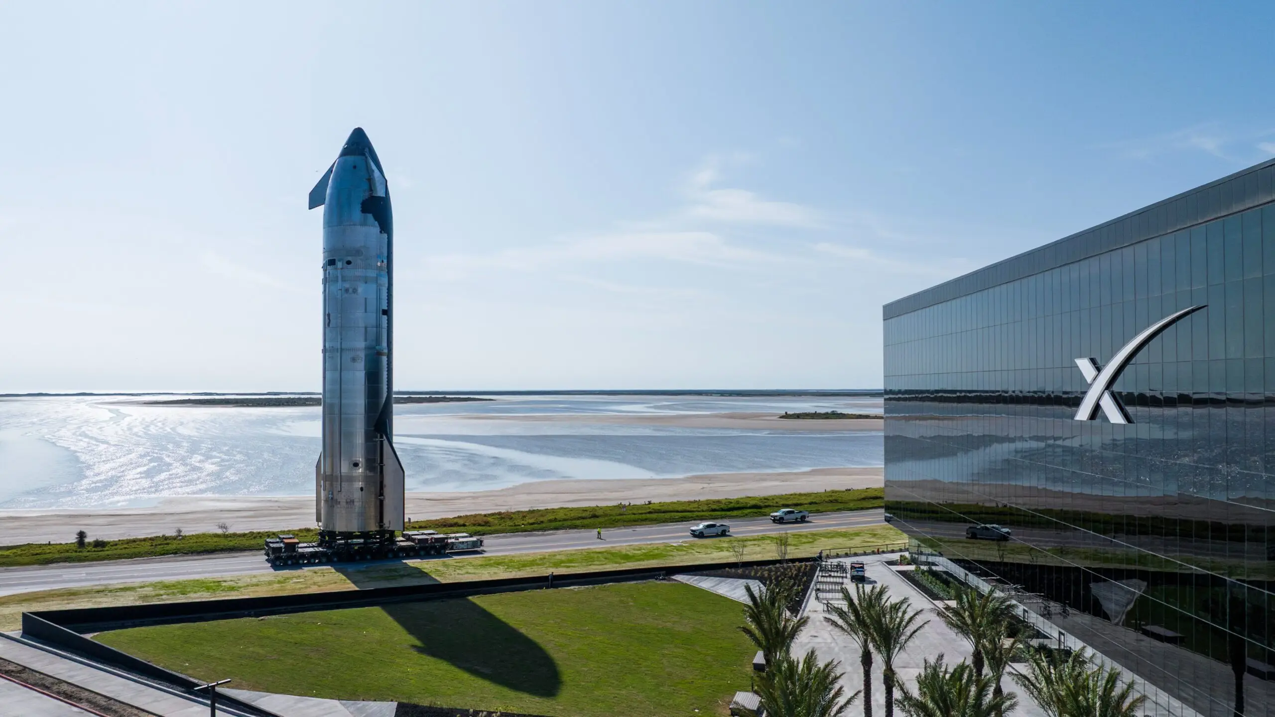 Starship rocket prototype displayed beside the SpaceX Starbase building near the shoreline, showing what it’s like to visit Starbase.