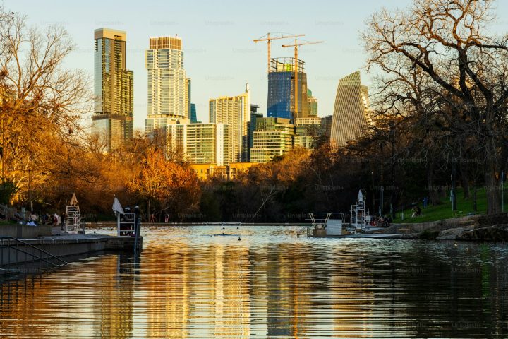 Fall color around Barton Springs Pool, with the downtown Austin skyline beyond.